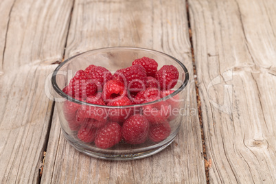 Clear glass bowl of ripe raspberries