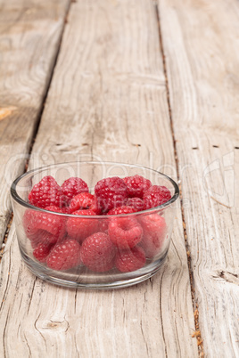 Clear glass bowl of ripe raspberries