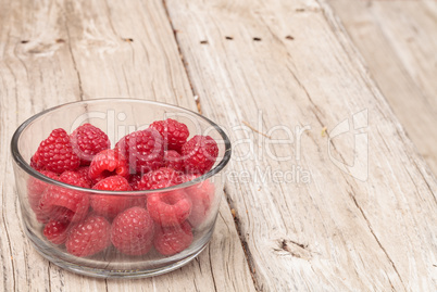 Clear glass bowl of ripe raspberries