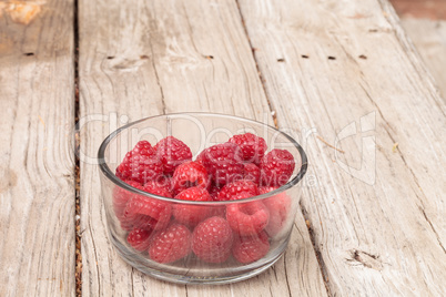 Clear glass bowl of ripe raspberries