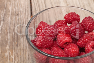 Clear glass bowl of ripe raspberries