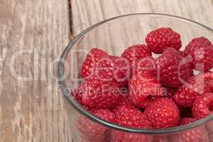 Clear glass bowl of ripe raspberries