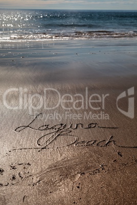 Laguna Beach written in script the wet sand