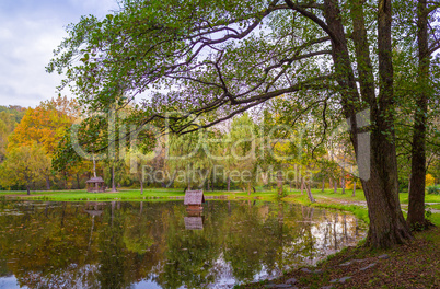 Autumn park with pond and wooden alcoves.