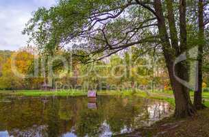 Autumn park with pond and wooden alcoves.