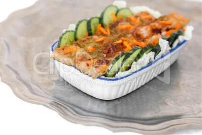 Fried fish with vegetables in a ceramic dish.