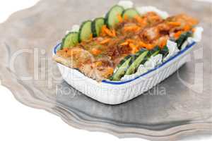 Fried fish with vegetables in a ceramic dish.