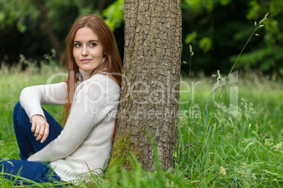 Beautiful Young Woman Sitting Leaning Against Tree