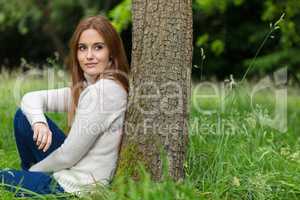 Beautiful Young Woman Sitting Leaning Against Tree