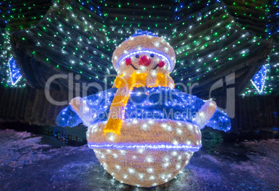 Snowman with bright lights and decorated fir.