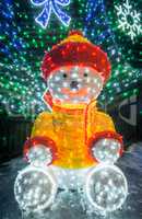 Teddy bear with bright lights and decorated fir.