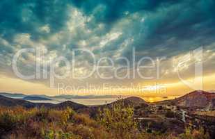 Colorful sunset view of mountains and sea and dramatic clouds on