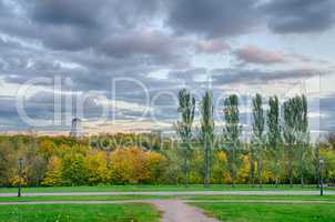 Colorful autumn park with church and clouds .