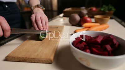 Female hands with knife cutting cucumber on board