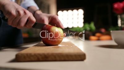 Woman with knife cutting apple on chopping board