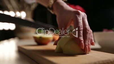 Female hand slicing peeled apple on cutting board