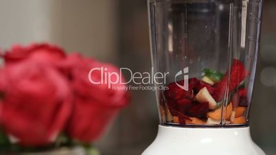 Woman adding vegetables and fruits into blender
