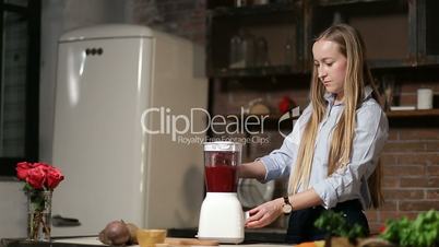 Charming woman blending beet smoothie with blender