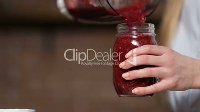 Closeup pouring beet smoothie from blender to jar
