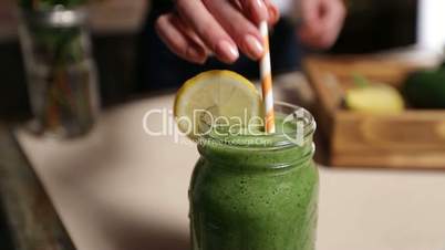 Woman decorating jar of healthy green smoothie
