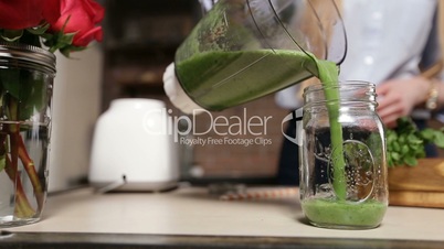 Pouring fresh green smoothie from blender into jar