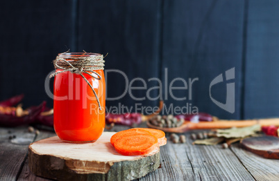 Jar of fresh carrot juice on a wooden surface