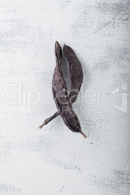 Two big brown Carobs on a wooden surface