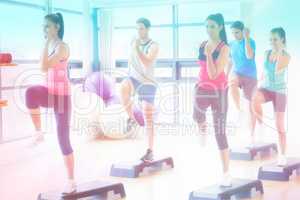 Composite image of instructor with fitness class performing step aerobics exercise
