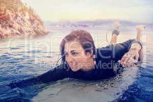 Composite image of young woman swimming over surfboard