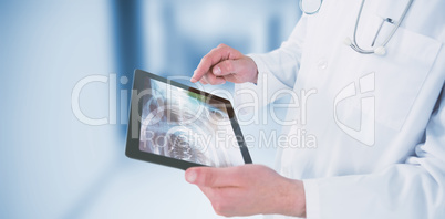 Composite image of doctor using digital tablet