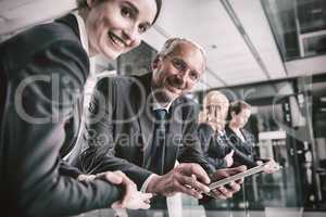 Portrait of businessman talking with colleague while holding digital tablet