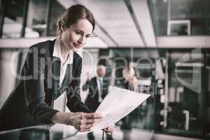 Businesswoman standing in corridor reading document in office