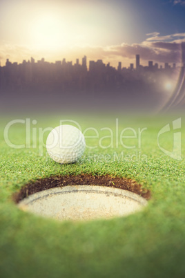 Composite image of golf ball at the edge of the hole