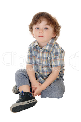 Little three year boy sitting on floor.