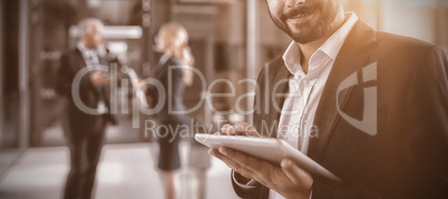 Businessman using digital tablet in office corridor