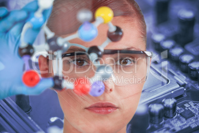 Composite image of portrait of female scientist holding molecular model