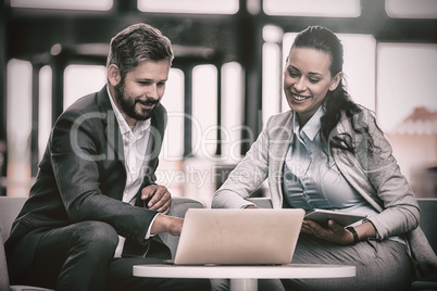 Businesspeople sitting and discussing over laptop