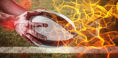 Composite image of hand rugby ball against abstract orange glowing black background