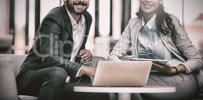 Happy businesspeople sitting with laptop