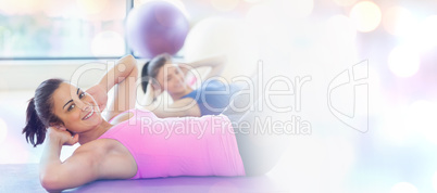 Composite image of two fit young women doing pilate exercises