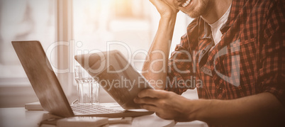 Graphic designer using laptop and digital tablet at his desk