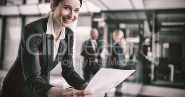 Businesswoman standing in corridor reading document in office