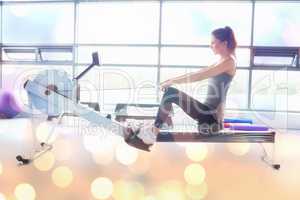 Composite image of woman working out on row machine