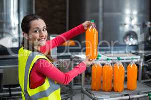 Female factory worker examining a bottle of juice