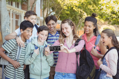 Happy students taking selfie on mobile phone in campus