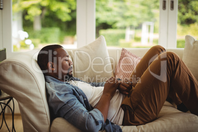 Man lying on sofa and using his smartwatch