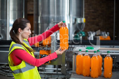 Female factory worker examining a bottle of juice
