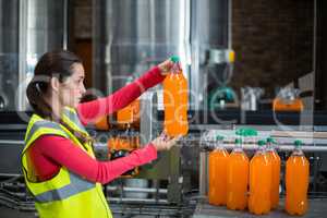 Female factory worker examining a bottle of juice