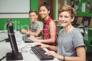 Smiling students studying in computer classroom