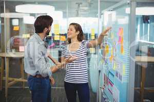 Male and female business executives discussing over whiteboard